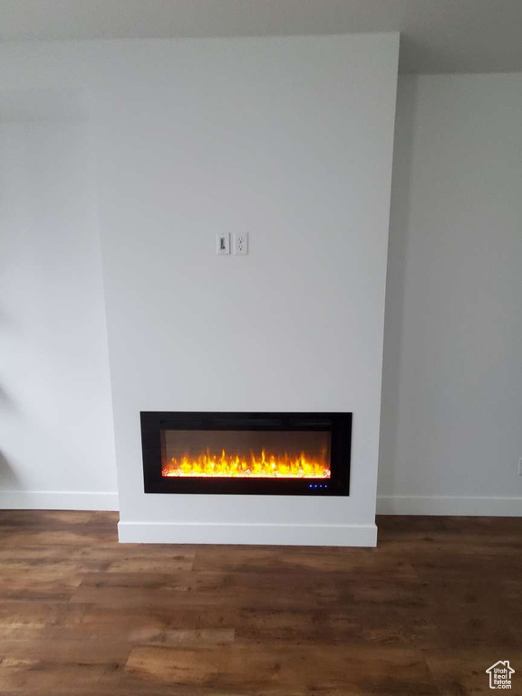 Detailed view of a glass covered fireplace, baseboards, and wood finished floors