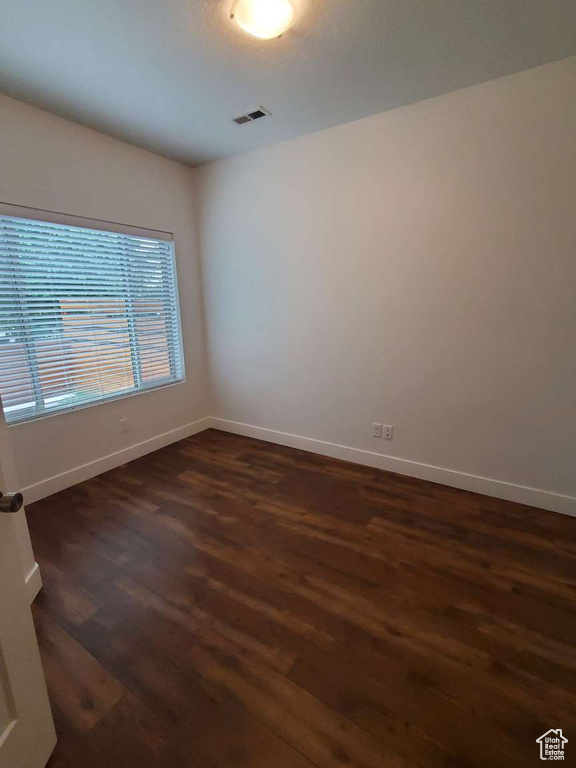 Empty room with dark wood-style flooring and baseboards