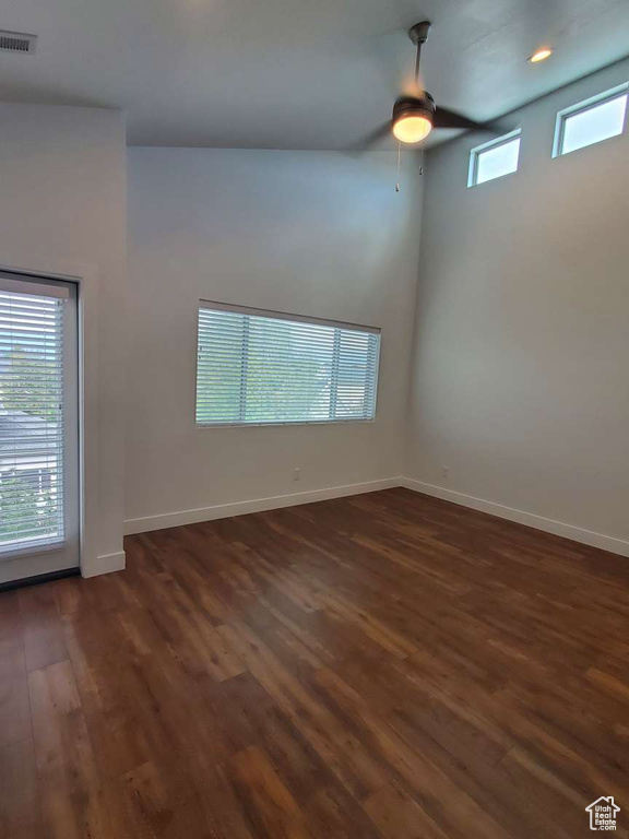 Empty room featuring a ceiling fan, dark wood-style flooring, and baseboards