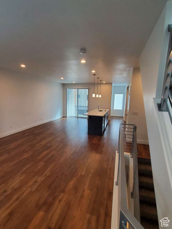 Unfurnished living room featuring a sink, dark wood-style floors, baseboards, and recessed lighting