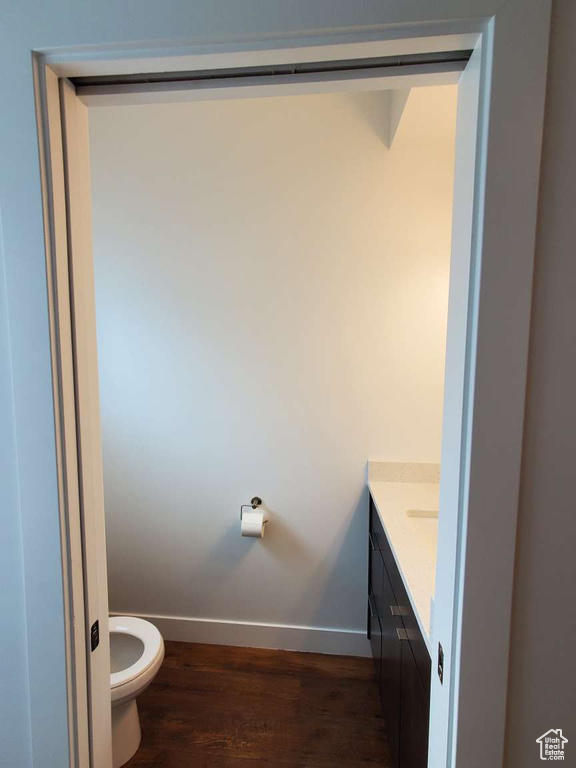 Bathroom featuring vanity, baseboards, toilet, and wood finished floors
