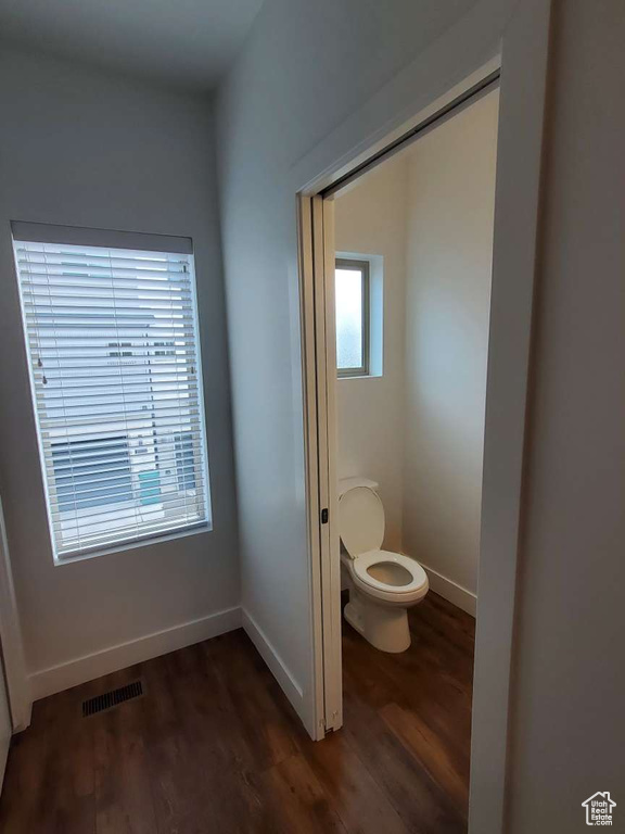 Bathroom featuring wood finished floors, toilet, and baseboards