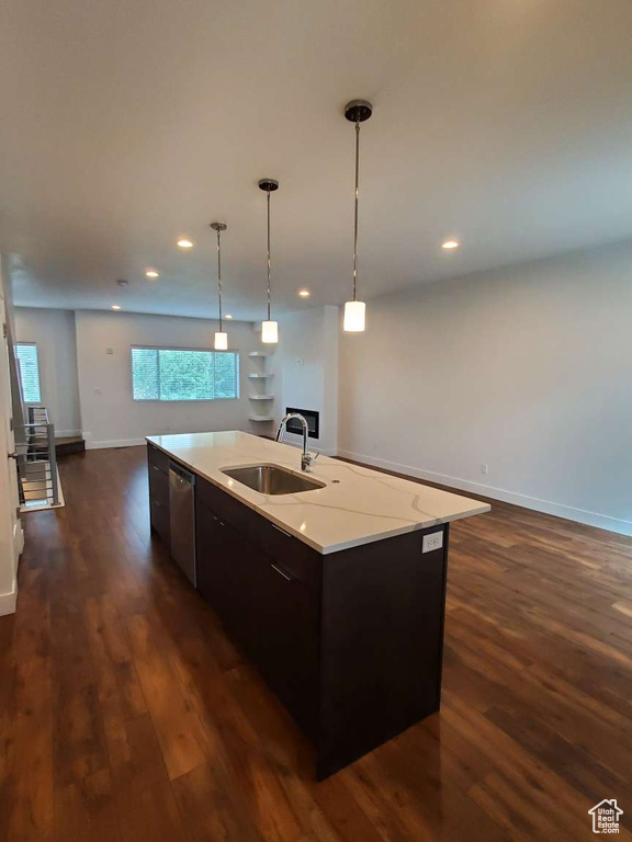 Kitchen with a sink, open floor plan, dishwasher, dark wood-style floors, and an island with sink