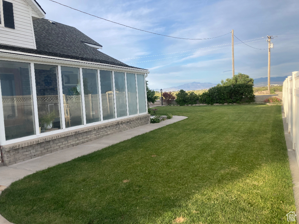 View of grassy yard with a sunroom and a mountain view