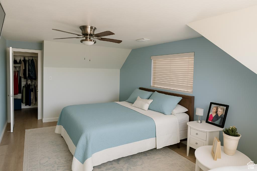 Bedroom featuring wood finished floors, a ceiling fan, vaulted ceiling, a closet, and baseboards