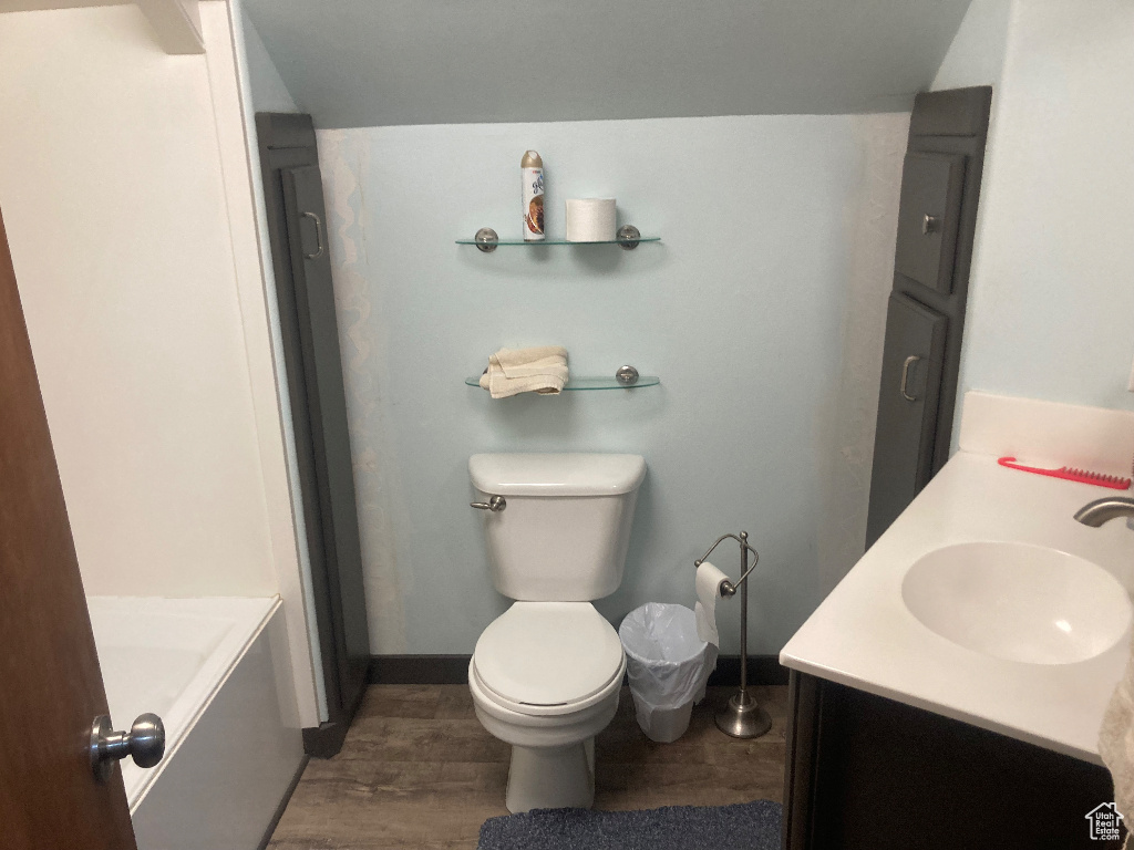 Full bath featuring vanity, a bathtub, wood finished floors, toilet, and baseboards
