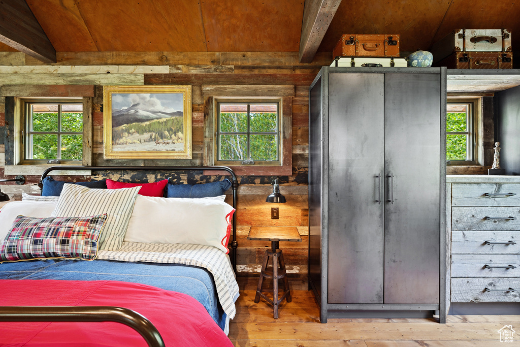 Bedroom featuring multiple windows, hardwood / wood-style flooring, and wooden ceiling with exposed beams