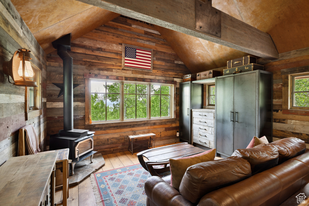 Living area with a wood stove, wood walls, vaulted ceiling, and hardwood / wood-style flooring