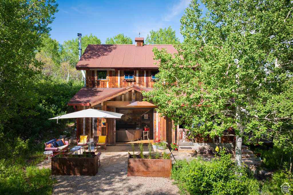 Back of house featuring a chimney, metal roof, and a patio