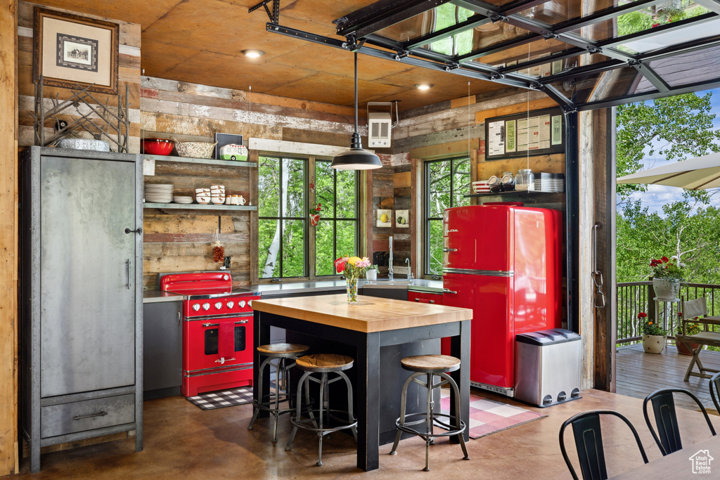 Kitchen featuring butcher block countertops, freestanding refrigerator, finished concrete flooring, open shelves, and decorative light fixtures