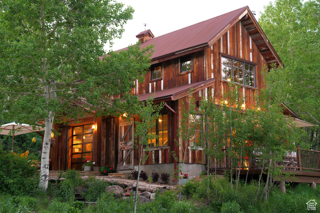 Back of property featuring metal roof, a chimney, and a deck
