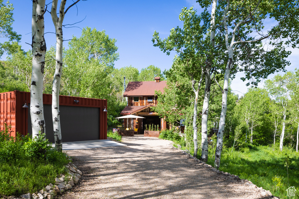 View of front of house featuring driveway, a chimney, and a garage