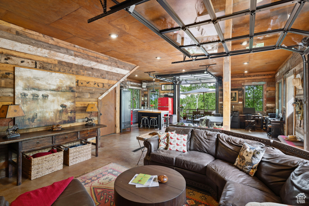 Living area with concrete flooring, wooden walls, and recessed lighting