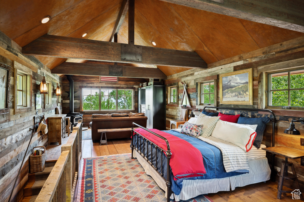 Bedroom with wood-type flooring, multiple windows, and wood walls