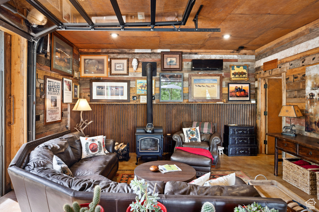 Living room with a wood stove, wooden walls, and concrete floors