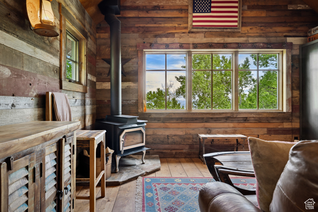 Sitting room featuring a wood stove, wooden walls, healthy amount of natural light, and hardwood / wood-style floors