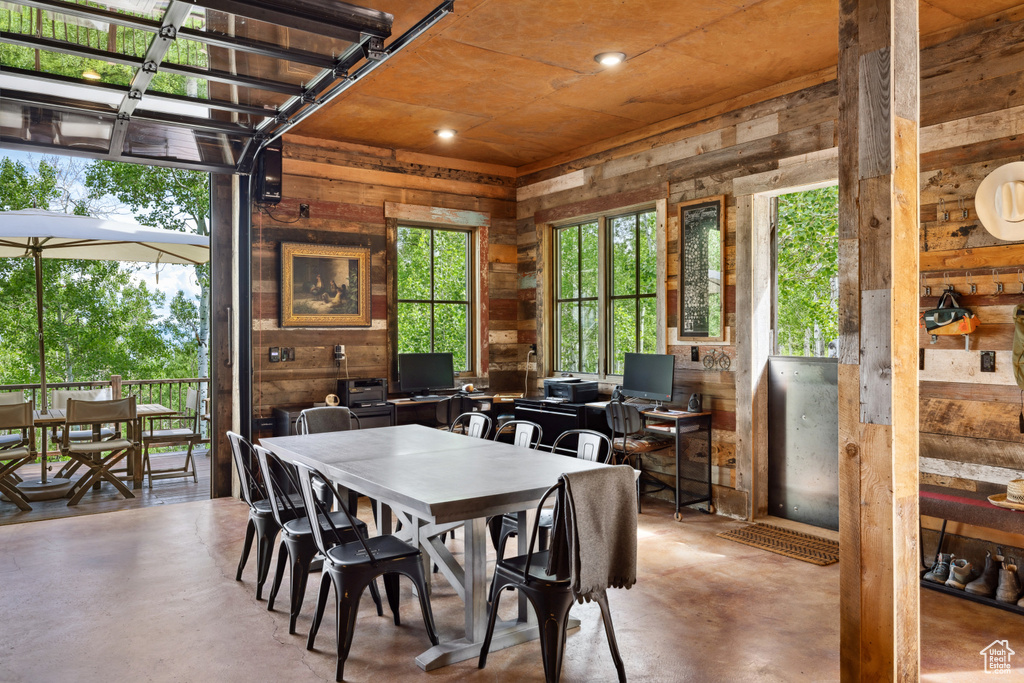 Dining space with concrete flooring, wooden walls, and recessed lighting