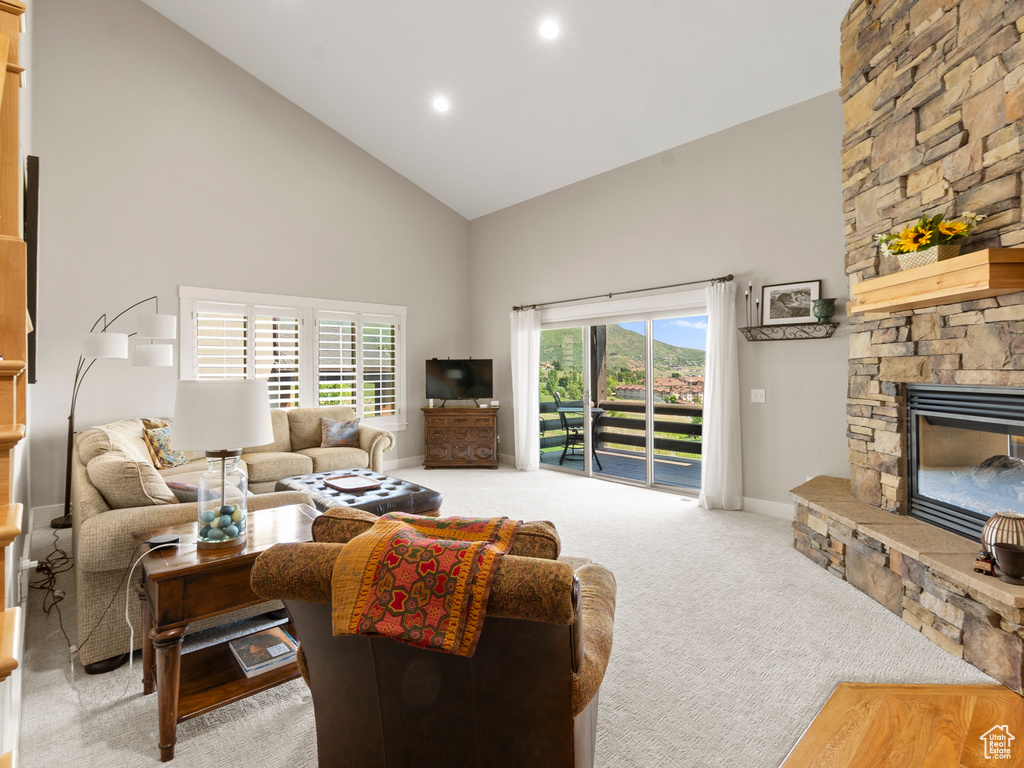 Carpeted living area with high vaulted ceiling, baseboards, a fireplace, and recessed lighting
