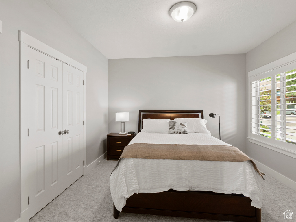 Bedroom with light colored carpet, baseboards, and a closet