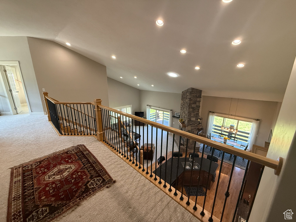 Hallway with an upstairs landing, recessed lighting, vaulted ceiling, carpet floors, and a chandelier