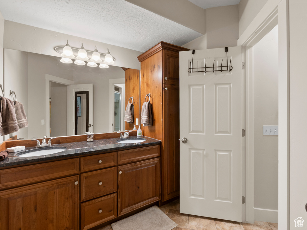 Full bath with double vanity and a textured ceiling