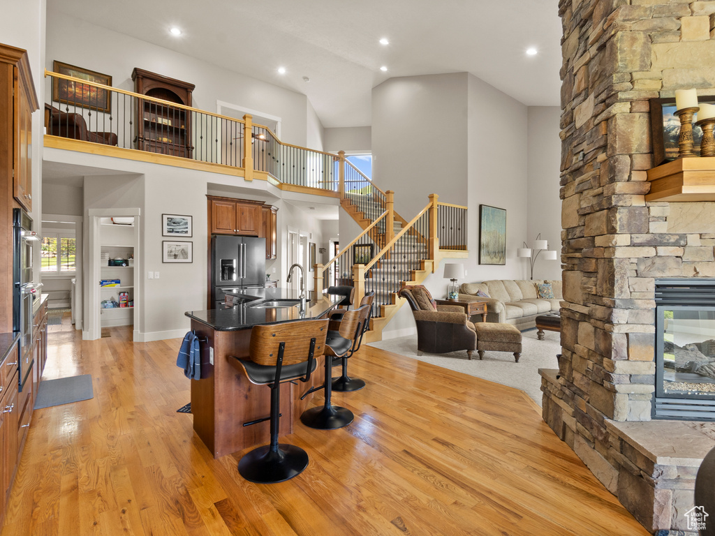 Kitchen with stainless steel appliances, a kitchen bar, a sink, a stone fireplace, and brown cabinetry