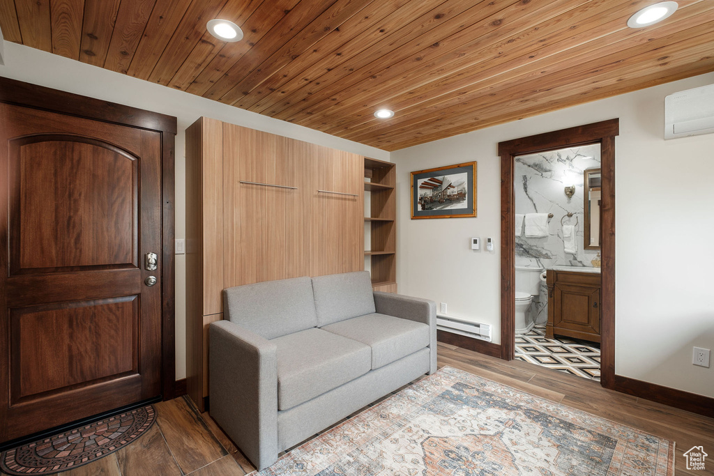 Living area featuring a baseboard radiator, recessed lighting, light wood-style flooring, an AC wall unit, and baseboards