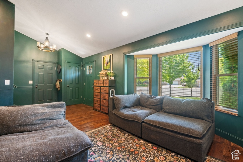 Living room featuring wood finished floors, a chandelier, lofted ceiling, and recessed lighting