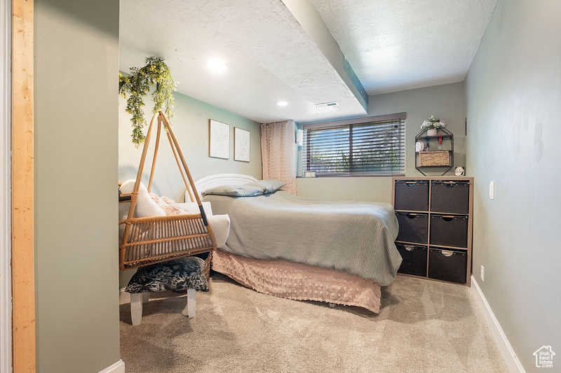 Carpeted bedroom featuring baseboards and a textured ceiling