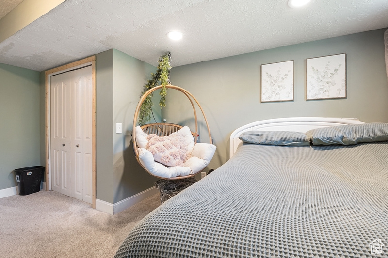 Bedroom with carpet flooring, baseboards, a closet, recessed lighting, and a textured ceiling