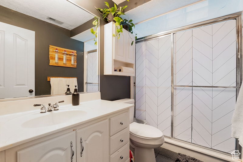 Bathroom with toilet, vanity, and a stall shower