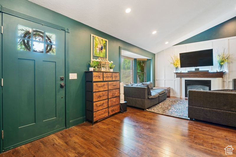 Foyer with vaulted ceiling, wood-type flooring, healthy amount of natural light, recessed lighting, and a glass covered fireplace