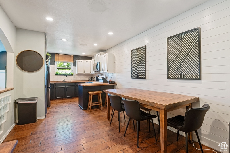 Dining area with hardwood / wood-style floors, arched walkways, recessed lighting, and wood walls