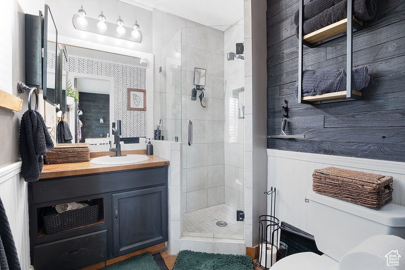 Bathroom with a stall shower, toilet, vanity, and wainscoting