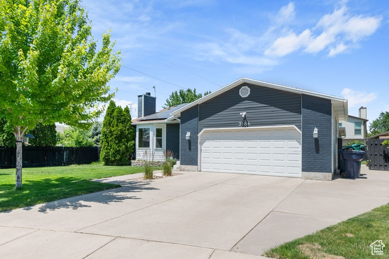 View of front of property featuring a chimney, an attached garage, concrete driveway, and brick siding