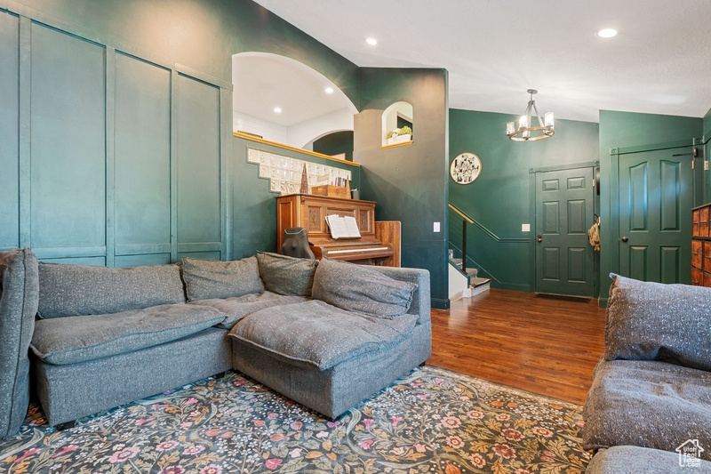 Living room with wood finished floors, stairs, a chandelier, baseboards, and recessed lighting