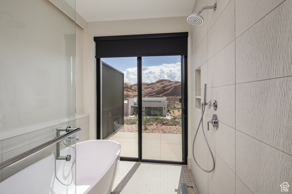 Bathroom featuring a freestanding tub, a mountain view, tile patterned flooring, a shower, and tile walls