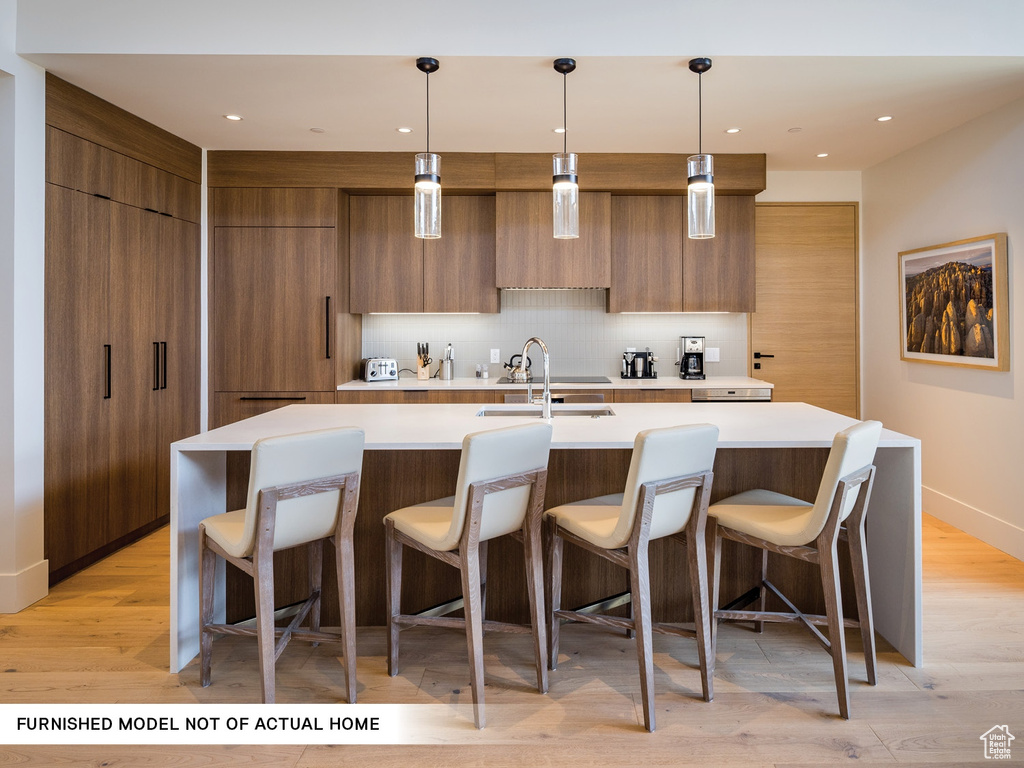 Kitchen featuring modern cabinets, brown cabinets, light countertops, and recessed lighting