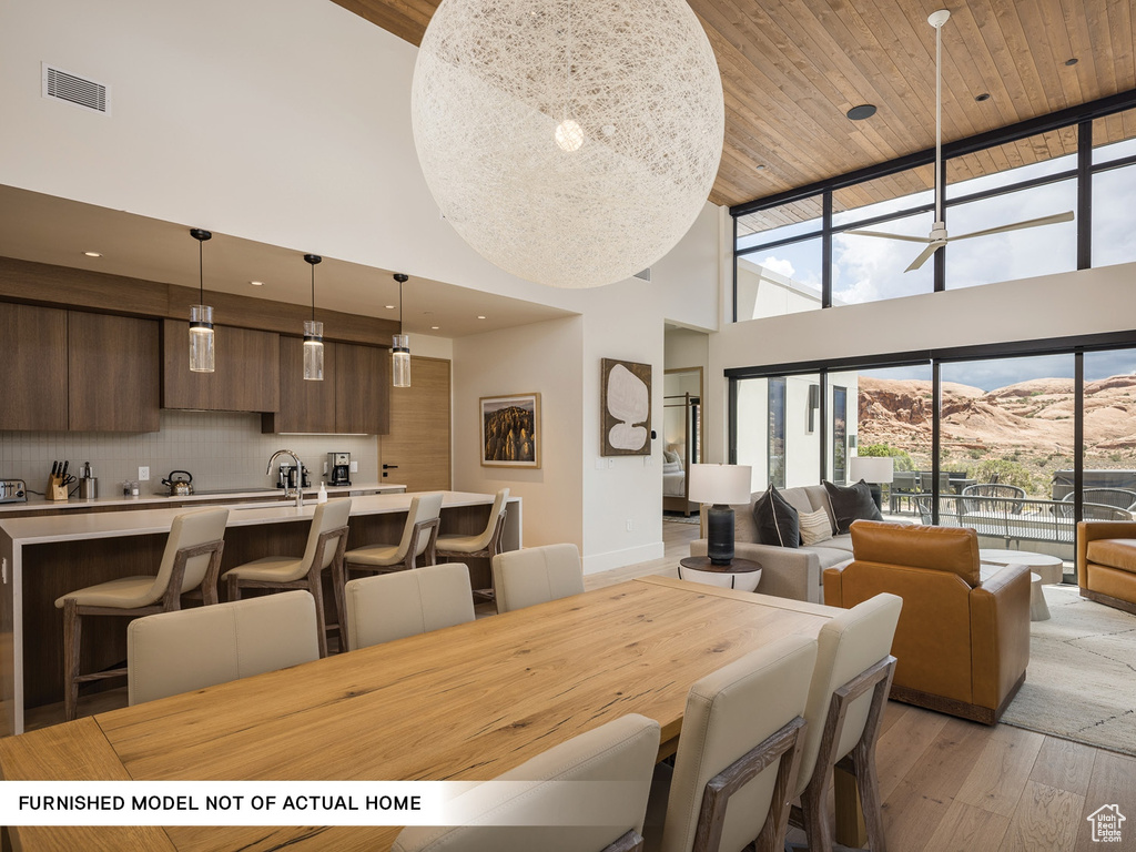 Dining area featuring a high ceiling, light wood-style flooring, and baseboards