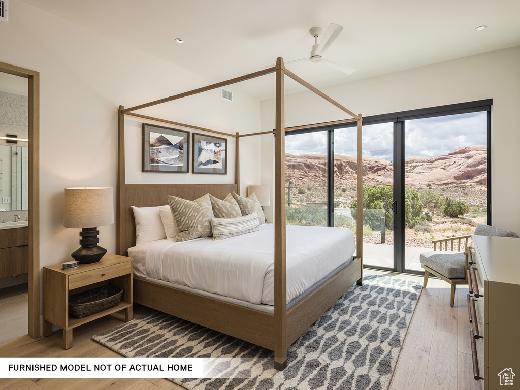 Bedroom with access to outside, wood finished floors, multiple windows, ensuite bath, and recessed lighting