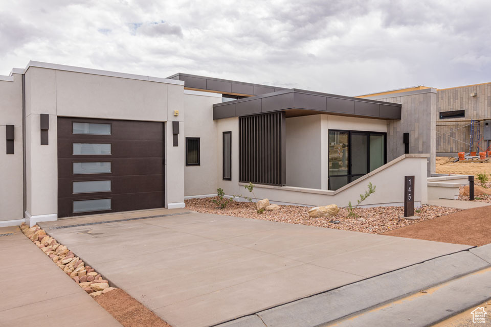 Contemporary home featuring concrete driveway, a garage, and stucco siding