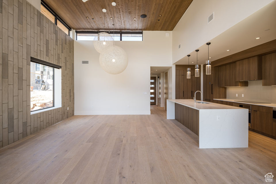 Kitchen featuring modern cabinets, a high ceiling, light countertops, light wood-style floors, and wood ceiling