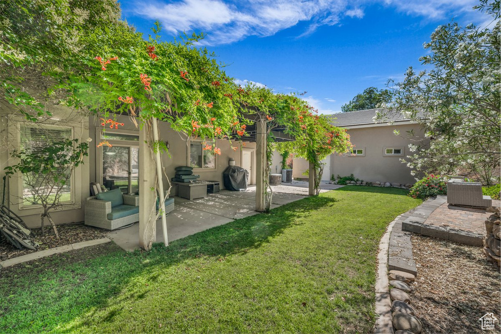 Back of property with a patio area, a yard, and stucco siding
