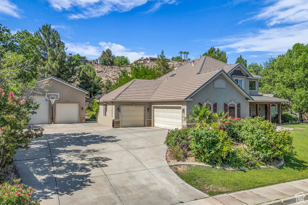 View of front of property featuring concrete driveway, a garage, stucco siding, a tiled roof, and a front lawn