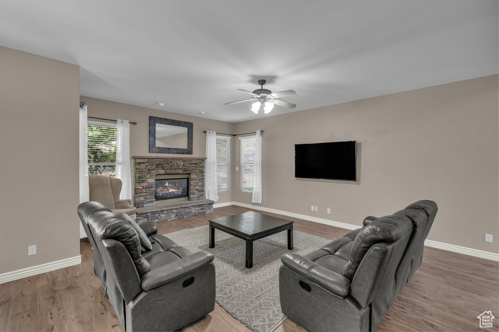 Living area featuring a fireplace, wood finished floors, and ceiling fan