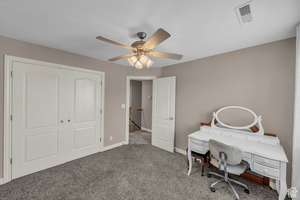 Carpeted home office with a ceiling fan and baseboards