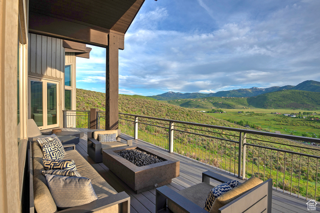 Wooden deck featuring a mountain view and an outdoor living space with a fire pit