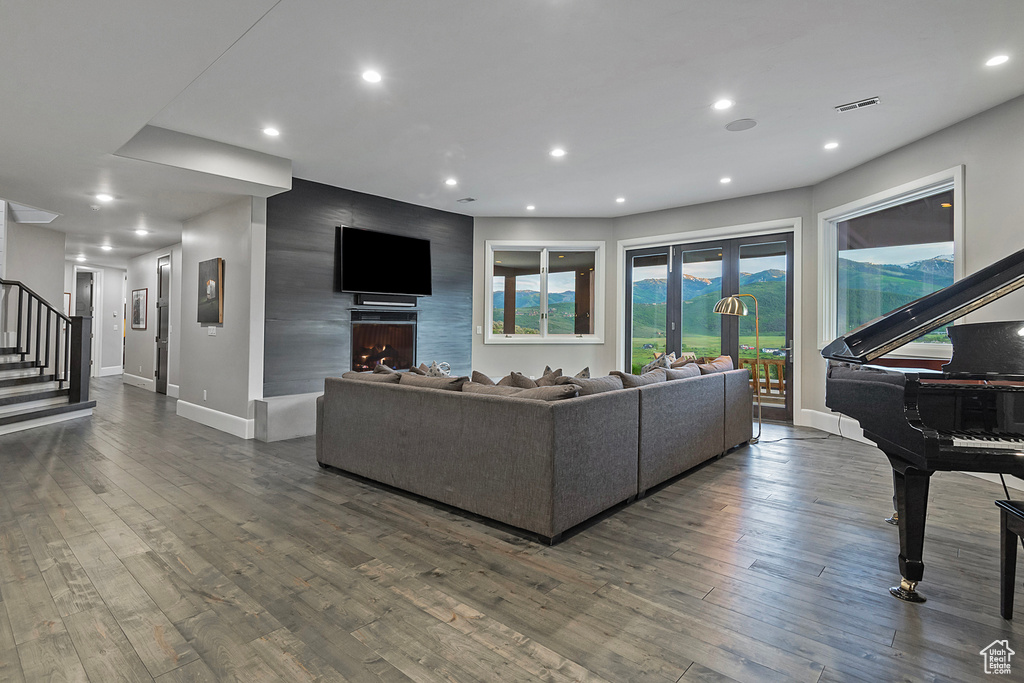 Living area featuring dark wood finished floors, stairs, baseboards, recessed lighting, and a large fireplace
