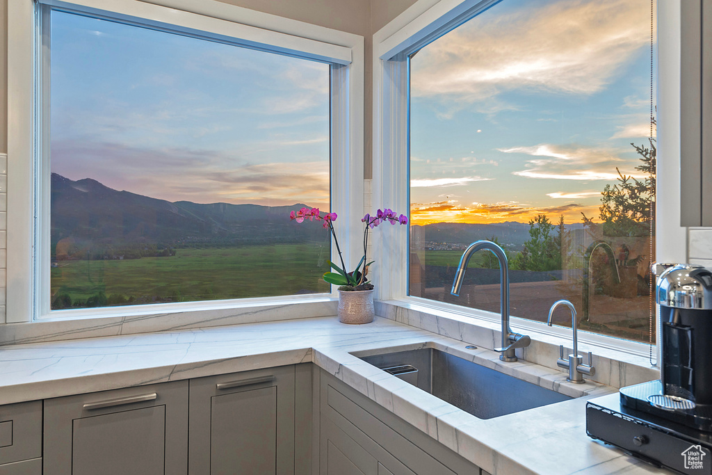 Kitchen featuring a sink, gray cabinetry, a mountain view, and light stone countertops