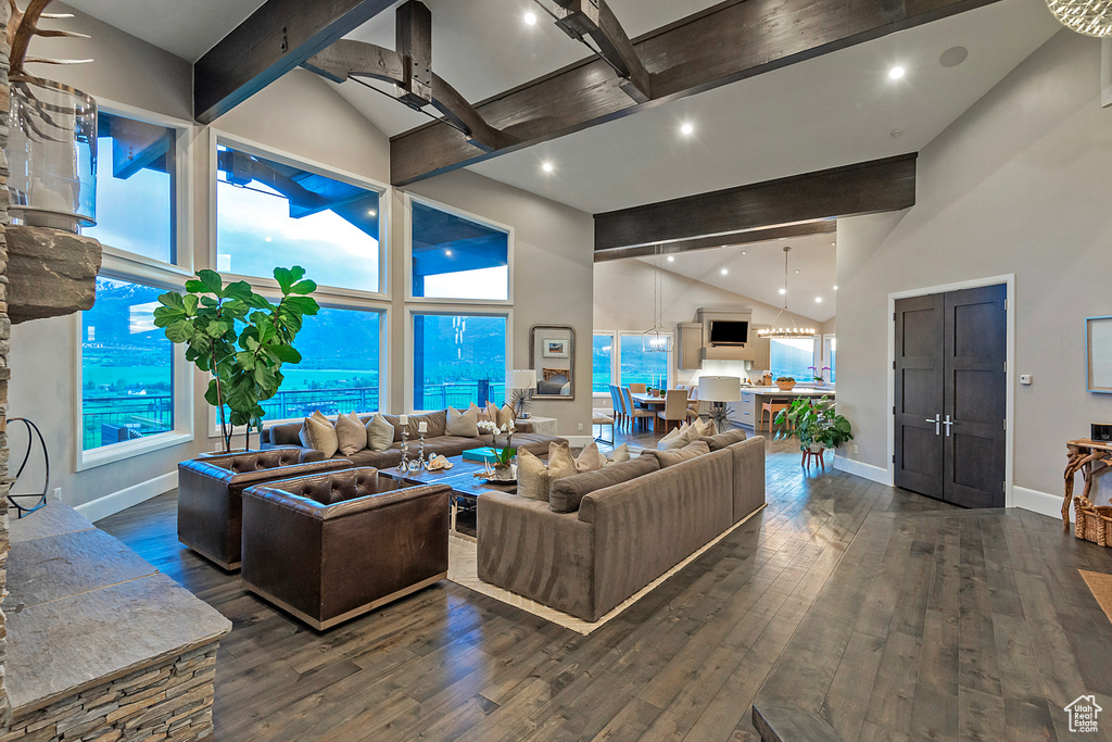 Living area featuring high vaulted ceiling, beamed ceiling, baseboards, hardwood / wood-style flooring, and a ceiling fan